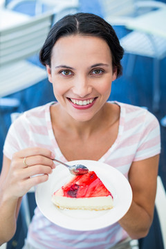 微笑的女人在吃一个蛋糕