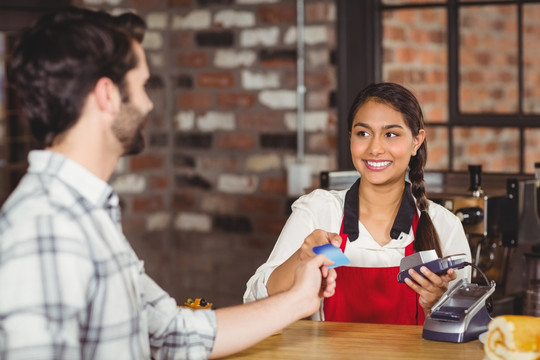 顾客将信用卡交给咖啡店的服务员