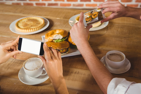在咖啡馆里使用手机拍早餐的夫妇