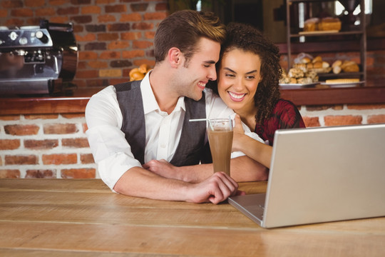 年轻夫妇在咖啡馆里用笔记本电脑