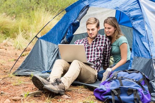 在帐篷里用笔记本电脑的夫妇