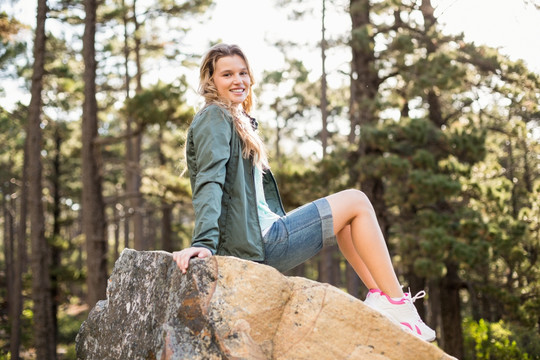 微笑的女人坐在岩石上