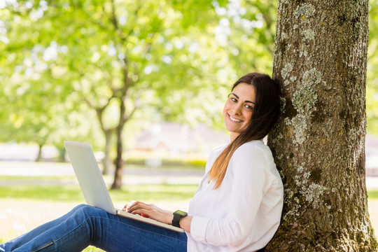 坐在树下用笔记搬电脑的女人