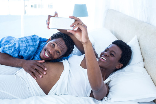 躺在床上拿着手机自拍的夫妇