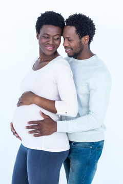 微笑的男人拥抱着怀孕的妻子