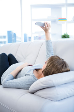 躺在沙发上使用手机自拍的孕妇