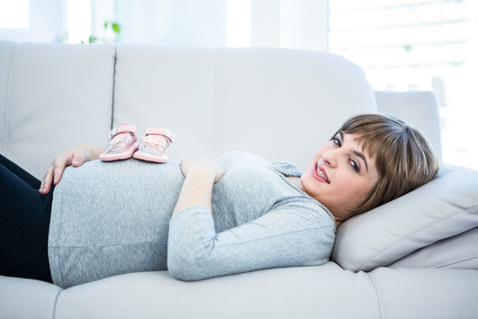 孕妇看着放在肚子上的婴儿鞋