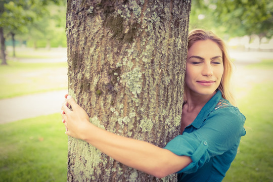 微笑的女人抱着一棵大树