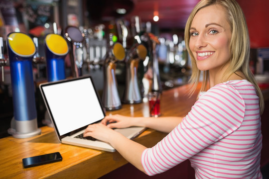 在酒吧使用笔记本电脑的商务女人