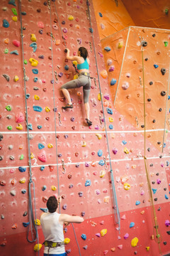 在健身房里爬攀岩的年轻女人