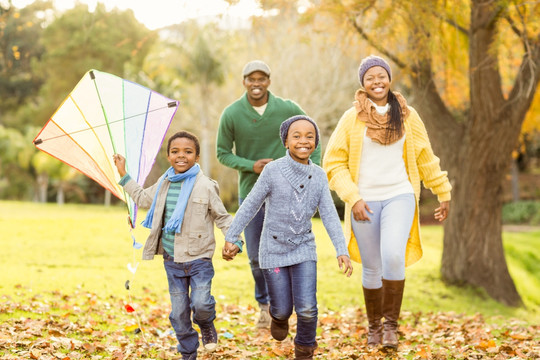 在秋天的公园里放风筝的家人