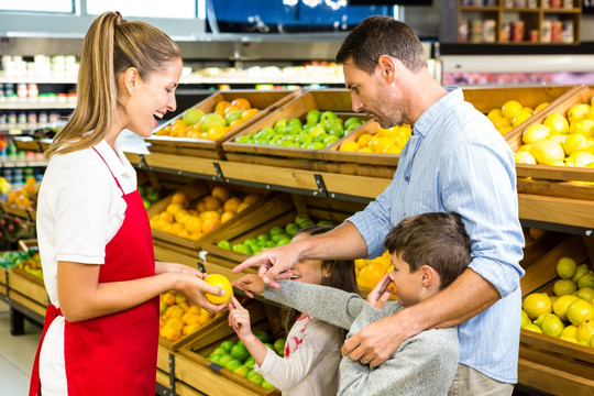 在超市里向顾客介绍水果的女员工