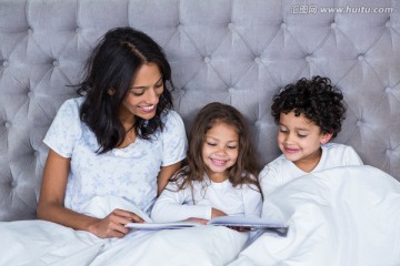 坐在床上看书的母亲和孩子们