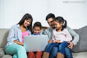 微笑着看着笔记本电脑的一家人