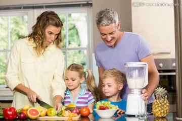 在厨房里教孩子切蔬菜的父母