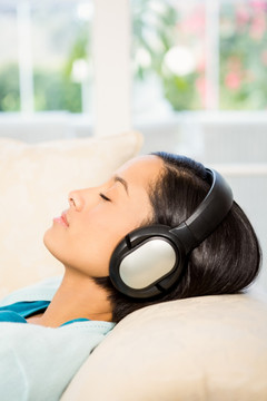 躺在沙发上戴着耳机听歌的女人