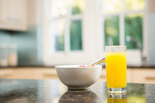 餐桌上的一杯橙汁和一碗麦片