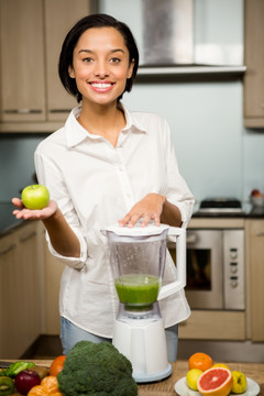 微笑的女人在厨房里拿着一个苹果