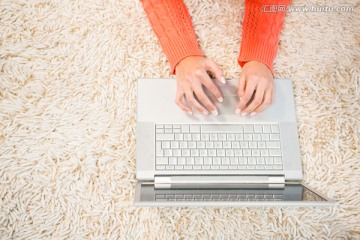 趴在地毯上使用笔记本电脑的女人