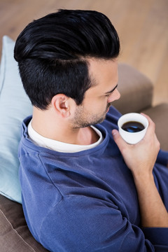 坐在沙发上喝咖啡的男人