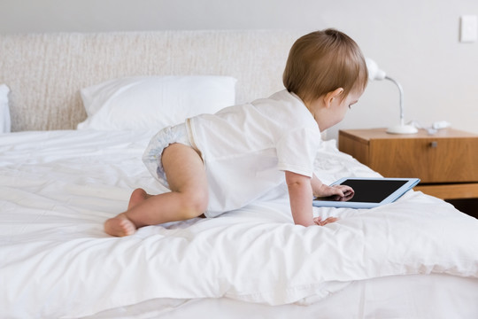 可爱的婴儿在床上使用平板电脑