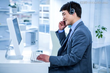 戴着耳机在电脑上工作的商务男人