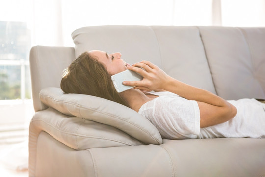 躺在沙发上使用手机打电话的女人
