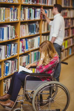 坐在轮椅上的学生在图书馆里看书