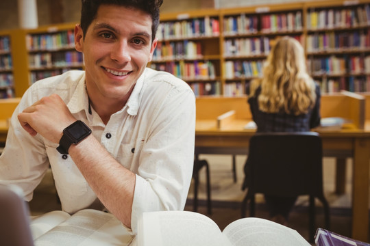 微笑的男学生在图书馆里看书