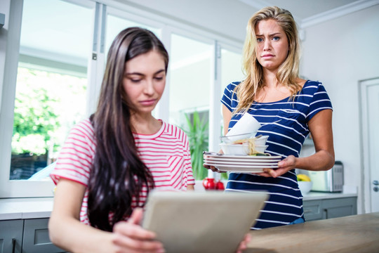 女人在厨房里给朋友展示脏盘子
