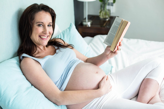 怀孕的女人在床上看书