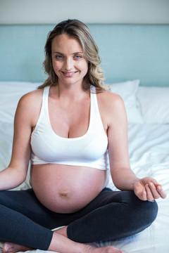 坐在床上练瑜伽的孕妇
