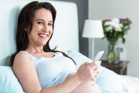 微笑着使用手机的孕妇