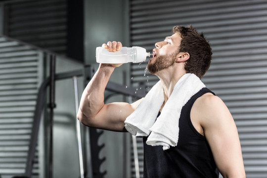 在健身房里喝水的男人