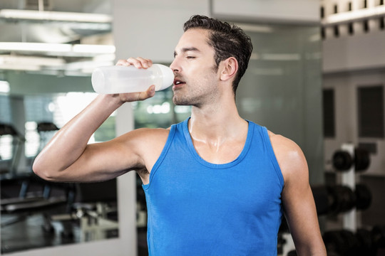 在健身房里喝水的男人