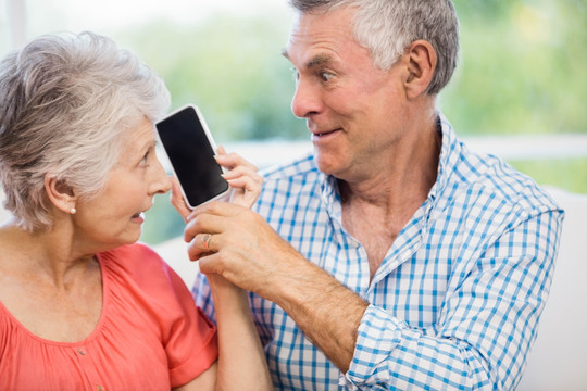 开心的老夫妇使用手机听音乐