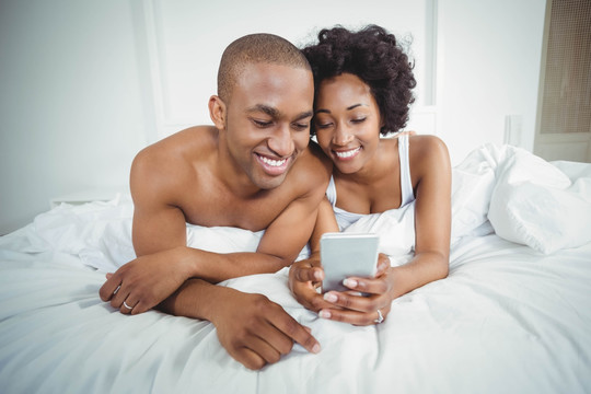 在床上使用手机的夫妇