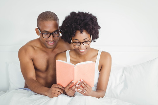 幸福的一对夫妇在床上看书