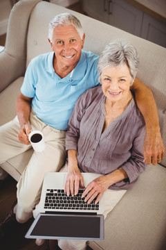 坐在沙发上用笔记本电脑老夫妇