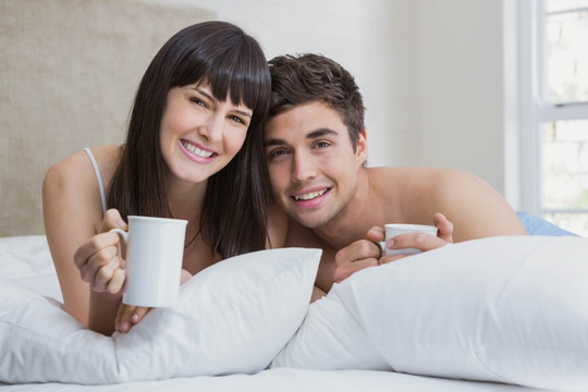 趴在床上喝咖啡的一对夫妇