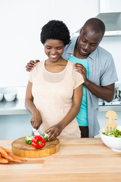男人看着怀孕的妻子切蔬菜