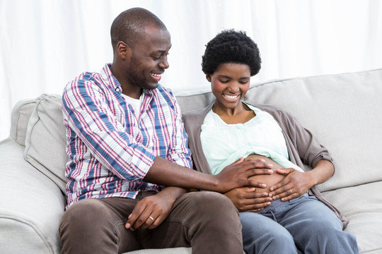 男人微笑着摸着怀孕妻子的肚子