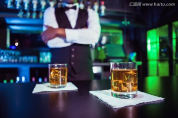 酒吧台上的两杯威士忌和酒吧侍者