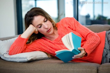 女人躺在沙发上读一本书
