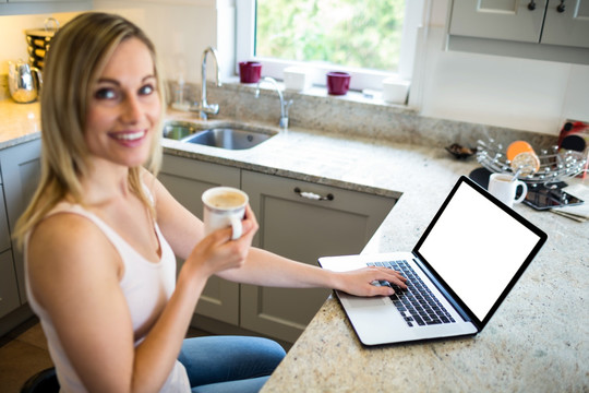 边喝咖啡边用笔记本电脑的女人