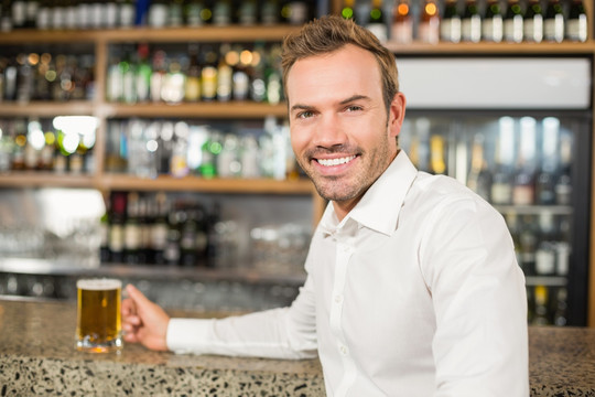 微笑的男人在酒吧里喝酒