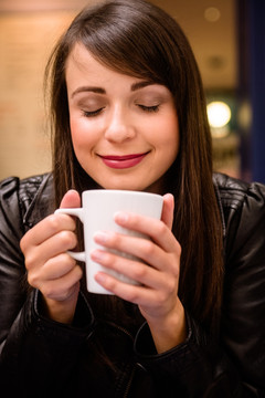 微笑的女人在闻一杯咖啡香味