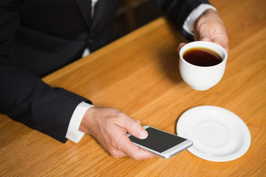 喝着咖啡使用手机的商务男人