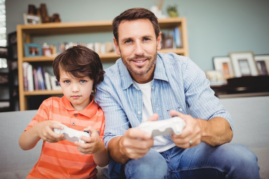 微笑的父亲和儿子在玩游戏机