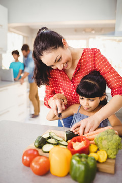 在教女儿切蔬菜的母亲